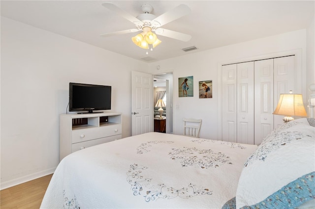 bedroom with baseboards, visible vents, a ceiling fan, wood finished floors, and a closet