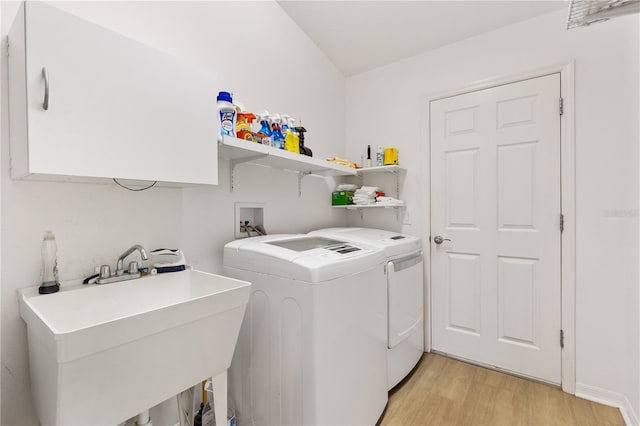 washroom with a sink, laundry area, washing machine and dryer, and light wood-style flooring