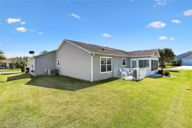 rear view of property with a sunroom, a lawn, and central air condition unit