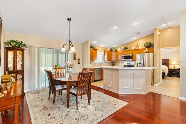 dining area featuring a notable chandelier, lofted ceiling, visible vents, light wood-type flooring, and baseboards