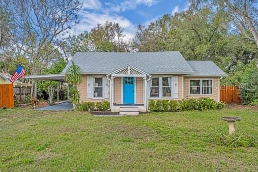 bungalow-style home with a carport, fence, and a front lawn