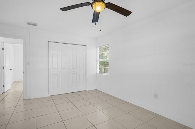 unfurnished bedroom featuring light tile patterned flooring, ceiling fan, and a closet