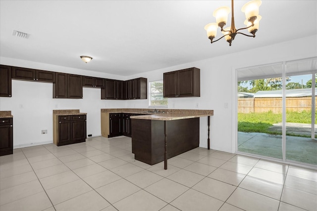 kitchen with light tile patterned flooring, dark brown cabinetry, decorative light fixtures, and a chandelier