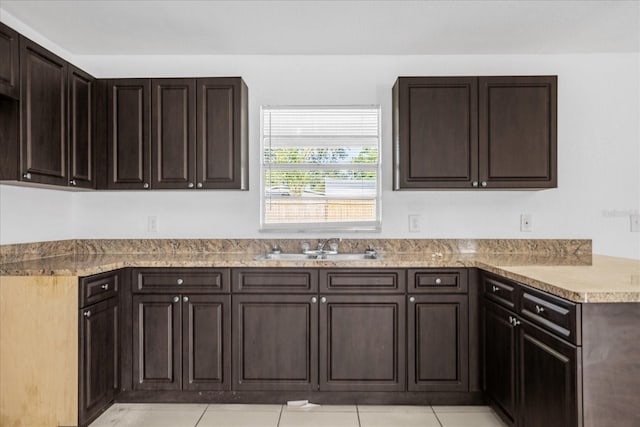 kitchen featuring dark brown cabinetry, sink, and light tile patterned floors