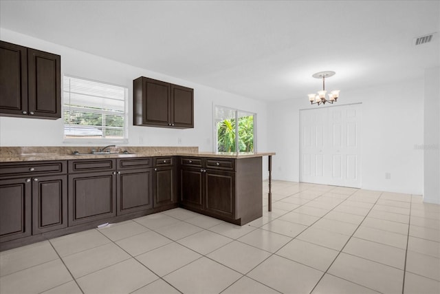 kitchen featuring decorative light fixtures, sink, kitchen peninsula, dark brown cabinets, and an inviting chandelier