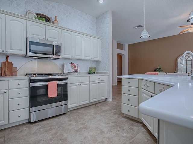 kitchen with sink, decorative light fixtures, a textured ceiling, appliances with stainless steel finishes, and white cabinets