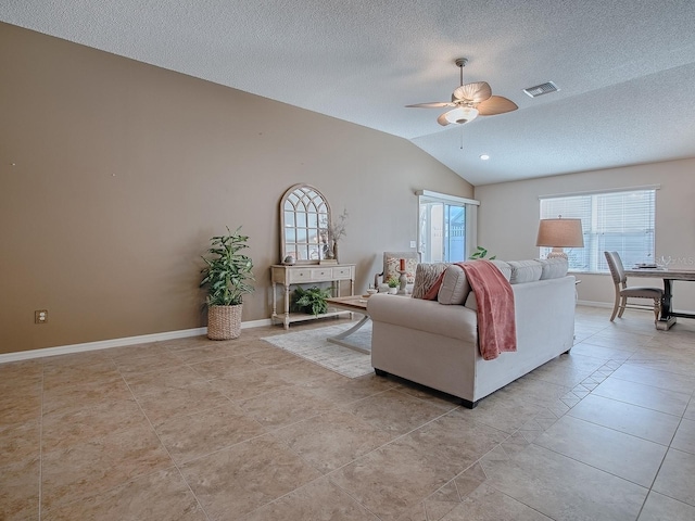 living room featuring ceiling fan, lofted ceiling, light tile patterned floors, and a textured ceiling