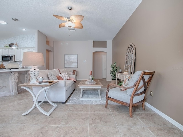 living room with light tile patterned flooring, vaulted ceiling, ceiling fan, and a textured ceiling