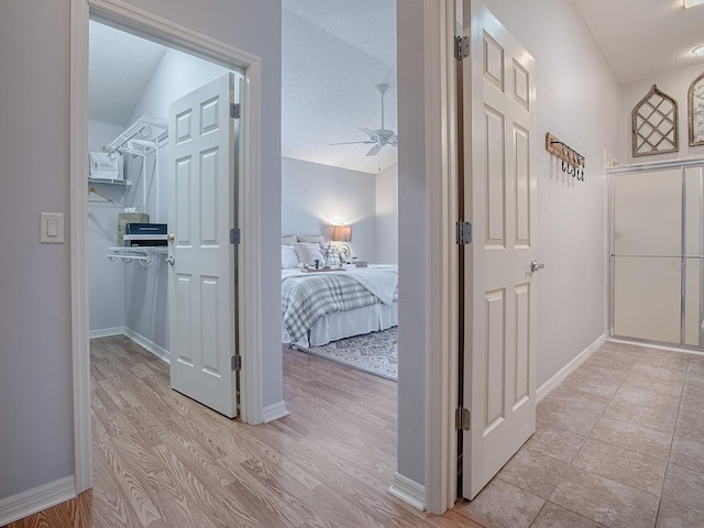 hallway with a textured ceiling and light hardwood / wood-style floors