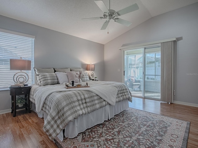 bedroom with wood-type flooring, lofted ceiling, access to outside, and a textured ceiling