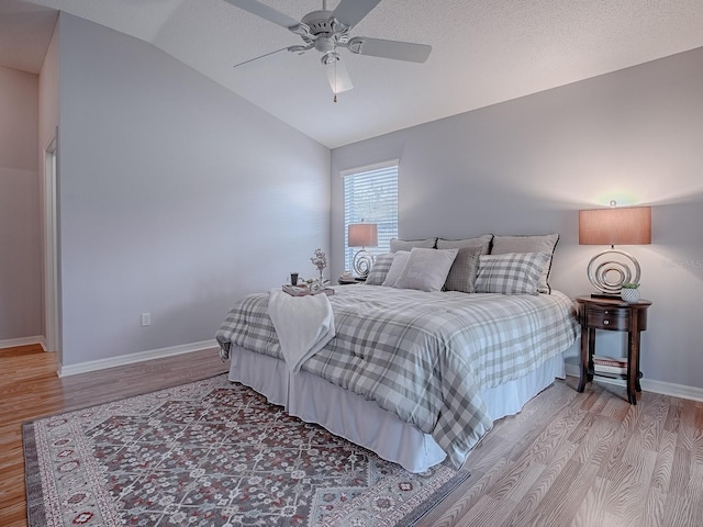 bedroom featuring ceiling fan, a textured ceiling, vaulted ceiling, and wood-type flooring