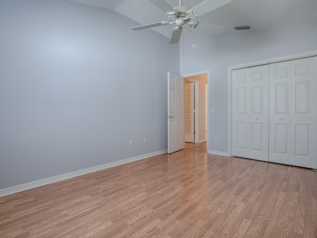 unfurnished bedroom featuring light hardwood / wood-style flooring, a closet, ceiling fan, and vaulted ceiling