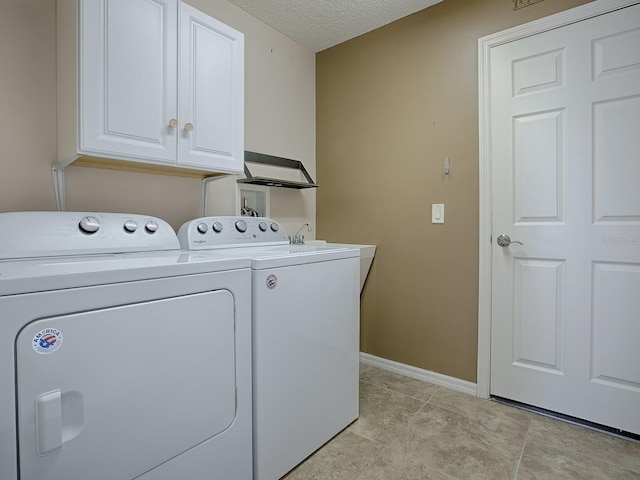 clothes washing area with cabinets, washing machine and dryer, a textured ceiling, and light tile patterned floors