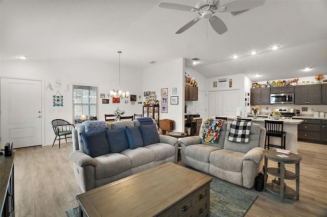 living room featuring ceiling fan with notable chandelier, lofted ceiling, and light hardwood / wood-style flooring