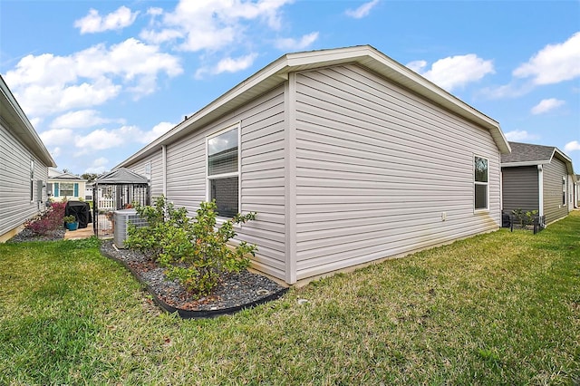 view of side of property featuring central AC unit, a yard, and a gazebo