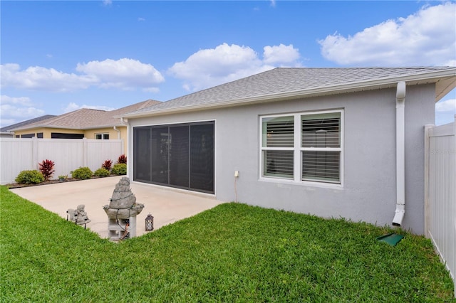 rear view of property featuring a yard, fence, stucco siding, and a patio