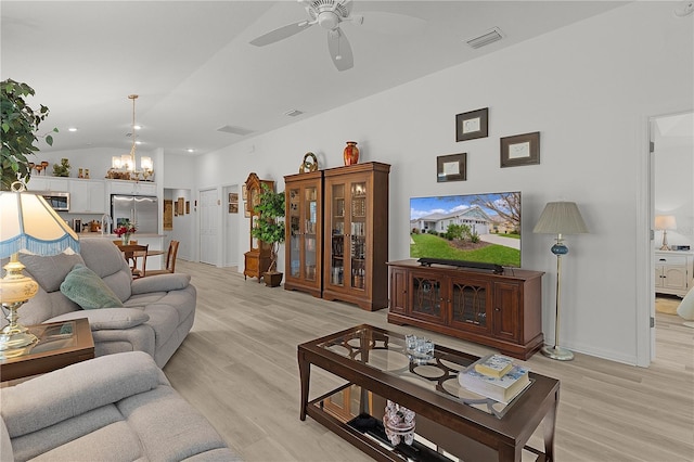 living area featuring lofted ceiling, light wood-style flooring, visible vents, and ceiling fan with notable chandelier