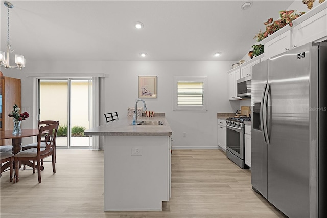 kitchen with stainless steel appliances, white cabinets, decorative light fixtures, and a sink