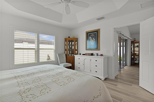 bedroom with ceiling fan, visible vents, light wood-style floors, access to outside, and a raised ceiling