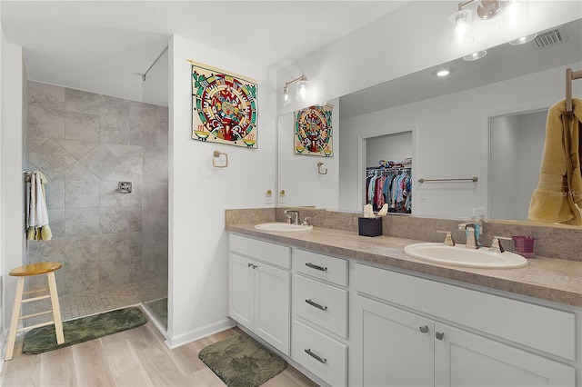 full bath with double vanity, a spacious closet, a sink, and wood finished floors