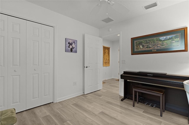 sitting room featuring light wood-style flooring, a ceiling fan, visible vents, and baseboards