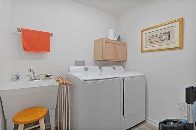 laundry room with cabinet space, light wood-style floors, a sink, independent washer and dryer, and baseboards