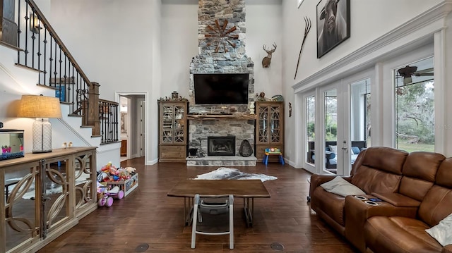 living room with a fireplace, french doors, a high ceiling, ceiling fan, and dark wood-type flooring