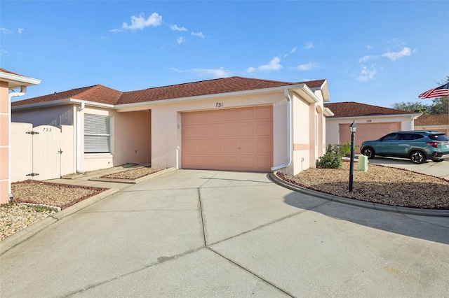 ranch-style home featuring stucco siding, roof with shingles, concrete driveway, and an attached garage