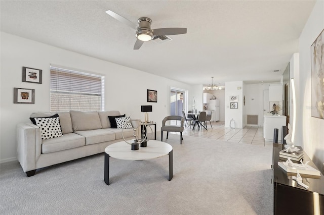 living area with ceiling fan with notable chandelier, light colored carpet, visible vents, and light tile patterned floors