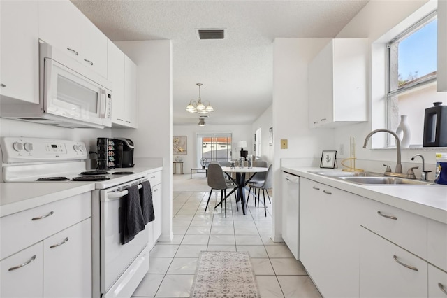 kitchen with white appliances, visible vents, light countertops, a chandelier, and a sink