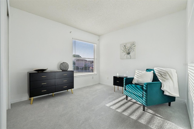 living area featuring light carpet, baseboards, and a textured ceiling