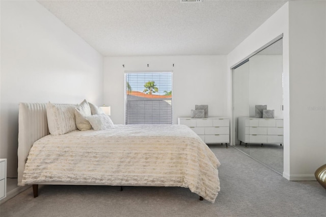 bedroom featuring carpet floors, a closet, visible vents, and a textured ceiling