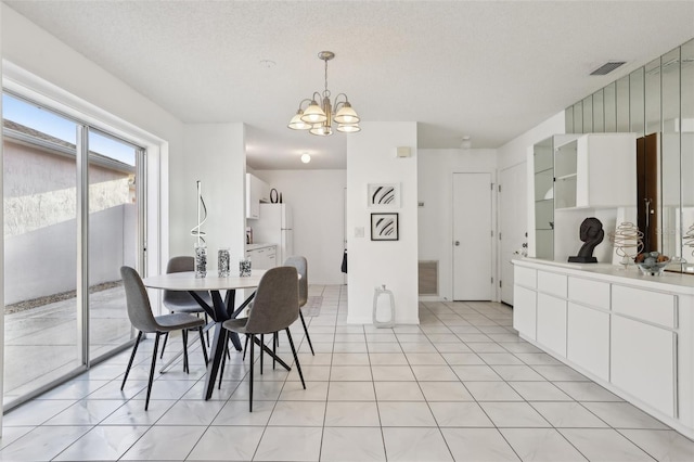 dining space with a chandelier, visible vents, a textured ceiling, and light tile patterned flooring