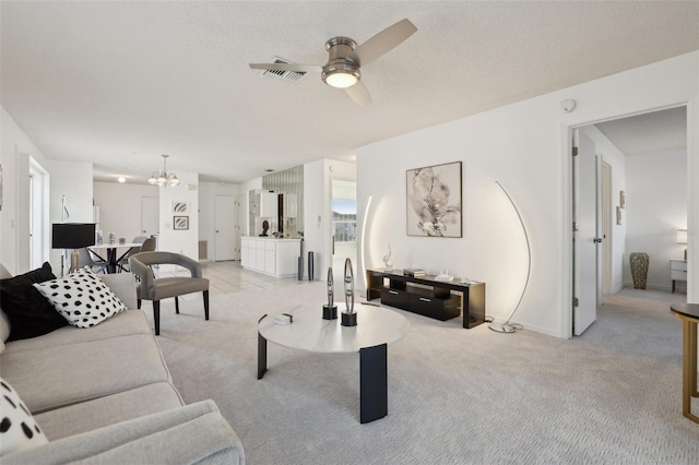 living room featuring light carpet, visible vents, ceiling fan with notable chandelier, and baseboards