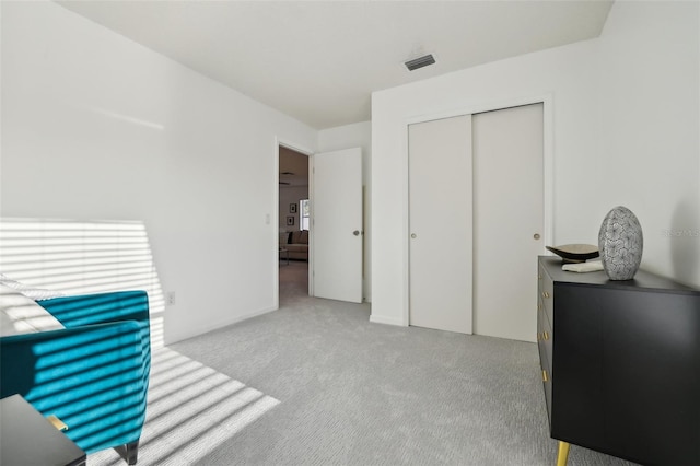 bedroom with light colored carpet, visible vents, and a closet