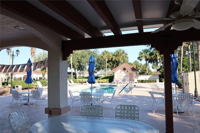 view of patio featuring outdoor dining space, a community pool, and a ceiling fan