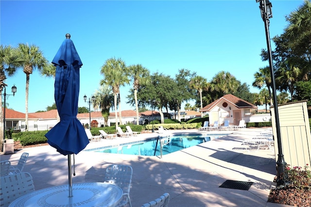community pool with a patio area and fence