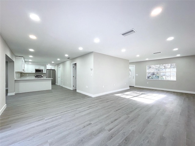 unfurnished living room with sink and light wood-type flooring