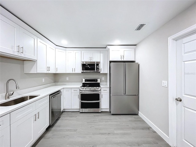 kitchen featuring appliances with stainless steel finishes, light hardwood / wood-style floors, sink, and white cabinets