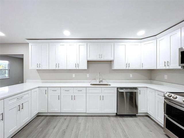 kitchen featuring white cabinetry, sink, light hardwood / wood-style flooring, and stainless steel appliances