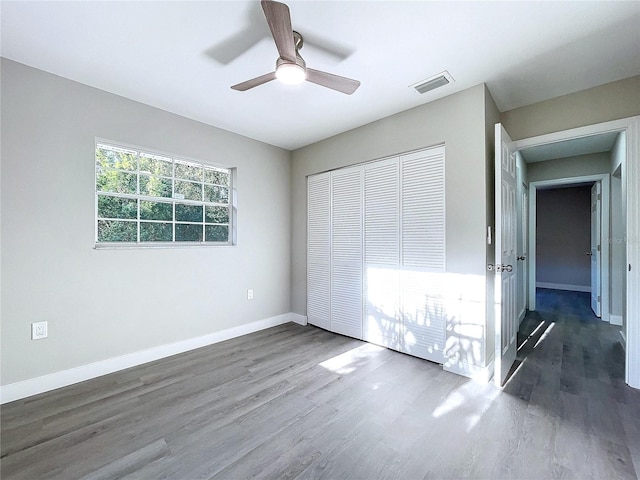 unfurnished bedroom featuring ceiling fan, dark hardwood / wood-style floors, and a closet