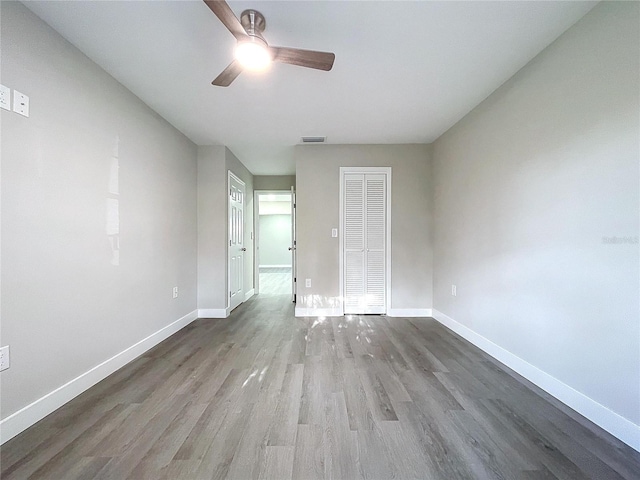 unfurnished bedroom with hardwood / wood-style flooring, ceiling fan, and a closet