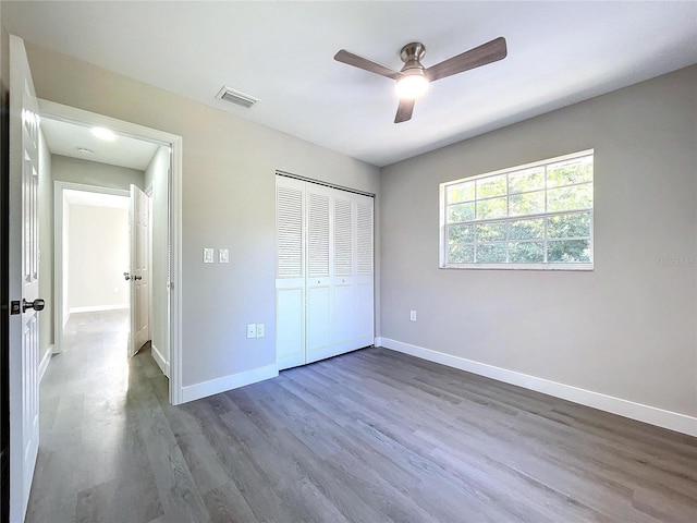 unfurnished bedroom with ceiling fan, wood-type flooring, and a closet