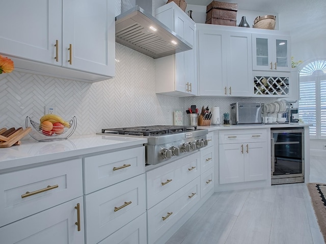 kitchen featuring glass insert cabinets, range hood, white cabinetry, and wine cooler