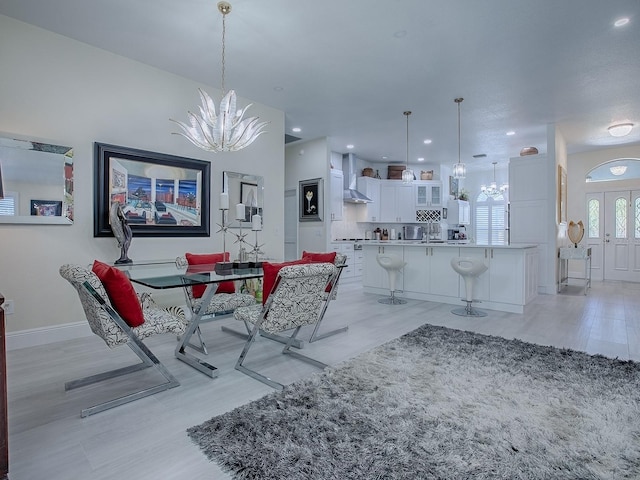 dining room featuring light wood-style floors, baseboards, and a notable chandelier