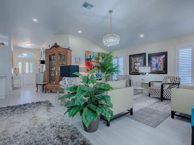 living area with an inviting chandelier, plenty of natural light, visible vents, and vaulted ceiling