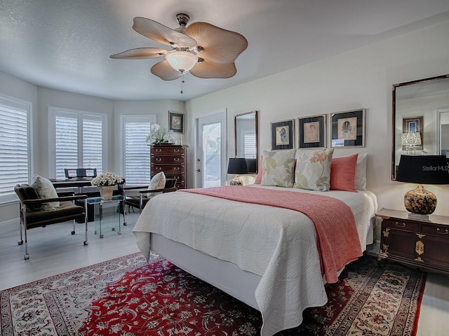 bedroom featuring a ceiling fan, access to outside, a textured ceiling, and wood finished floors