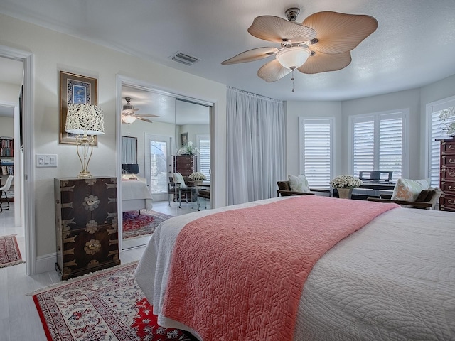 bedroom featuring a ceiling fan, visible vents, and multiple windows