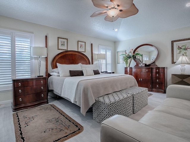 bedroom featuring a textured ceiling, light wood-style flooring, and a ceiling fan