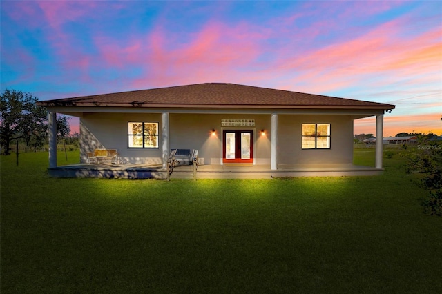 back of property featuring french doors, a lawn, a shingled roof, and stucco siding